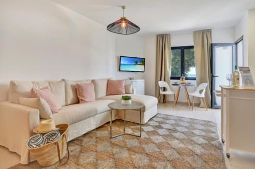 Luminoso loft moderno en Corralejo con sofá crema, vistas al mar, TV de pantalla plana y zona de comedor con vista al océano