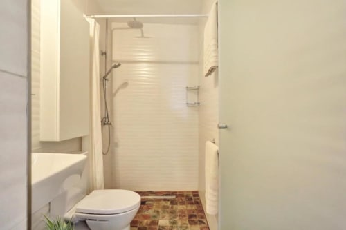 Baño moderno en apartamento de Corralejo con ducha, inodoro y piso de azulejos
