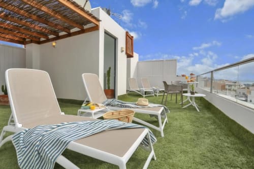 Terraza en la azotea de Kamalahouse en Corralejo con tumbonas, césped artificial, pérgola y vistas de la ciudad