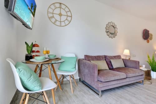 Moderno salón de apartamento en Corralejo con sofá púrpura, zona de comedor, vistas al mar y televisor de diseño contemporáneo
