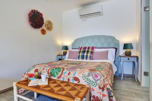 Habitación luminosa en Kamalahouse SL de Corralejo con cabecero azul, ropa de cama floral colorida y vistas al mar