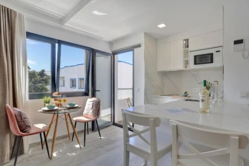 Cocina loft moderna y comedor con vista al mar en balcón de Corralejo, con muebles blancos y diseño contemporáneo