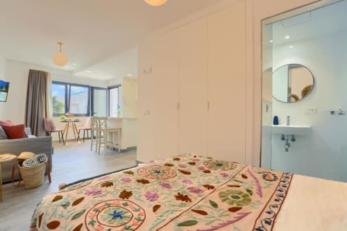Luminoso dormitorio tipo loft en Corralejo con ropa de cama floral, baño en suite, vistas al mar y zona de estar abierta
