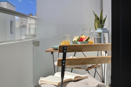 Moderna cocina estilo loft con estanterías de madera, productos frescos, plantas y libro abierto en la cama de Kamalahouse en Corralejo