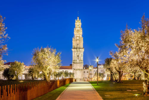 Torre dos Clérigos iluminada à noite no Porto com árvores e caminho iluminados, perto da Oporto Comfort Charming House