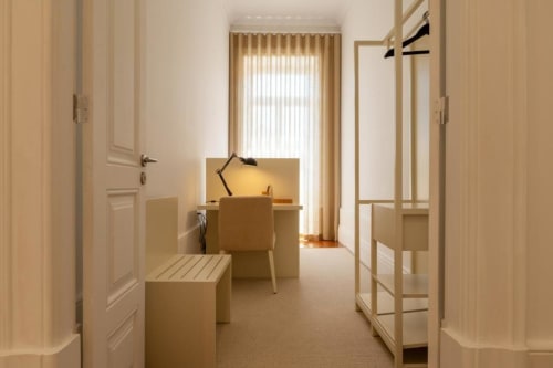 Quarto luminoso e minimalista na Oporto Comfort Charming House, Porto, com móveis em madeira e luz natural das janelas verticais