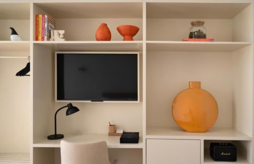 Unidade de prateleiras no quarto com TV, cerâmica laranja, livros e luminária de mesa preta na Oporto Comfort Charming House no Porto