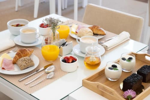 Elegante pequeno-almoço no Oporto Comfort Charming House com croissants, frutas frescas, sumo, café e pastéis no Porto.
