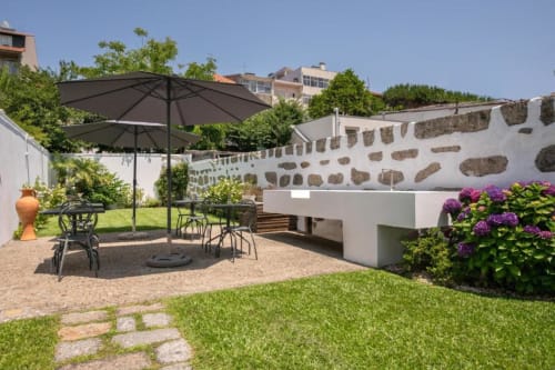 Pátio Porto BnB com área de estar, hortênsias roxas, guarda-chuvas e paredes de pedra