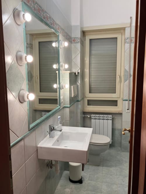 Bagno moderno presso Fairome Fleming B a Roma con specchio illuminato, lavabo bianco, toilet e pavimenti in piastrelle