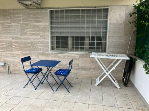 Area patio con tavolo e sedie pieghevoli blu, asse da stiro, presso l'appartamento Fairome Fleming a Roma