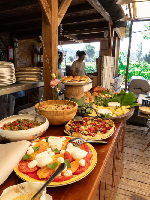 Buffet de Clos Bb avec pizza Caprese, pâtisseries, salades et charcuterie dans un cadre de terrasse rustique, Saint-Cyr sur