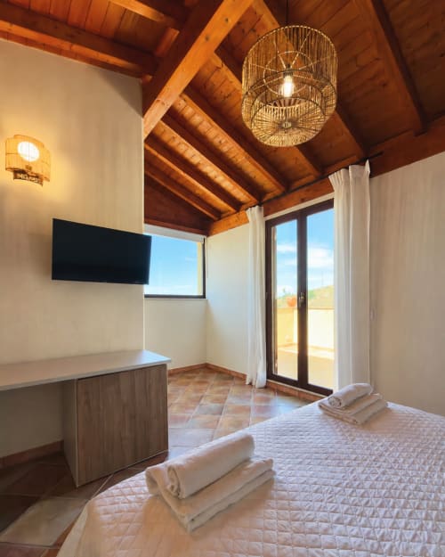 Camera Suite Rosmarino della villa Baglio Capo con travi in legno, vista lago, TV schermo piatto e accesso alla terrazza