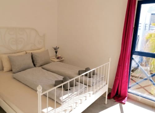 Helles Schlafzimmer im Casa del Sol Cottage, Morro Jable, mit weißem Metallbettgestell, beigefarbener Bettwäsche und Meerblick vom Balkon