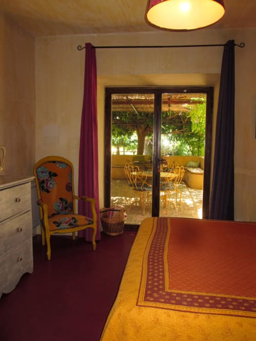 Bedroom at Clos Bb in Saint-Cyr sur Mer with terrace doors opening to garden views, orange chair, and burgundy accents