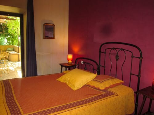 Bright bedroom at Clos BB in Saint-Cyr sur Mer with wrought iron bed, gold pillows, and magenta walls