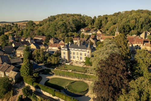 Vue aérienne du Château de Tharoiseau, élégante demeure couleur crème entourée de jardins paysagés et de boisés luxuriants
