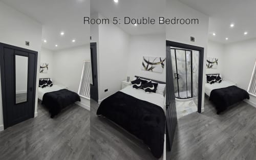 Modern double bedroom with two black four-poster beds, white bedding, and contemporary decor at Entrepreneur Stays cottage in