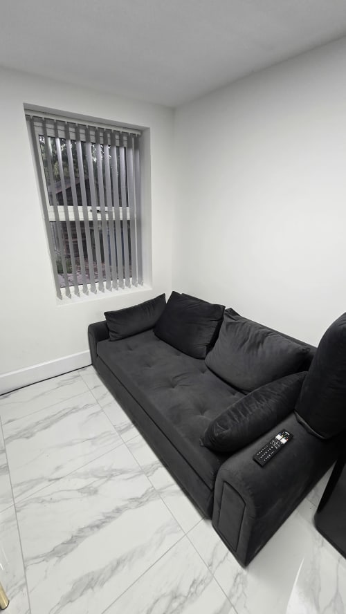Modern sitting area with black sofa, gray vertical blinds, marble flooring at Entrepreneur Stays cottage in Stafford