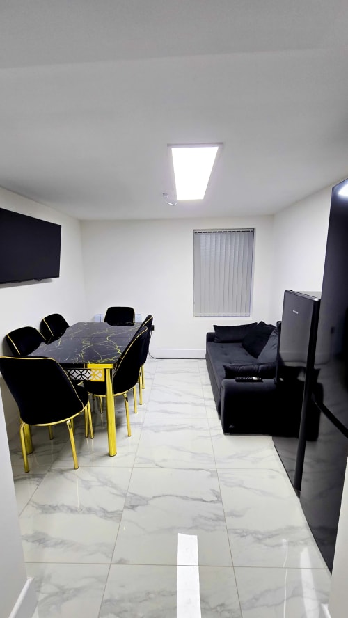 Modern open-plan living area with black and yellow dining table, seating, and TV in Stafford cottage
