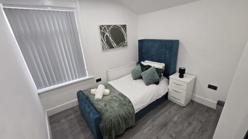 Modern bedroom at Entrepreneur Stays Stafford cottage with blue upholstered bed, white bedding, and contemporary décor