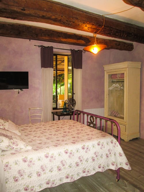 Affascinante camera da letto al Clos Bb di Saint-Cyr sur Mer con biancheria a fiori, travi a vista e porte che si affacciano sul giardino