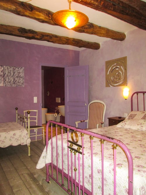 Affascinante camera al Clos Bb a Saint-Cyr sur Mer con pareti viola, travi in legno a vista e letto in ferro rosa