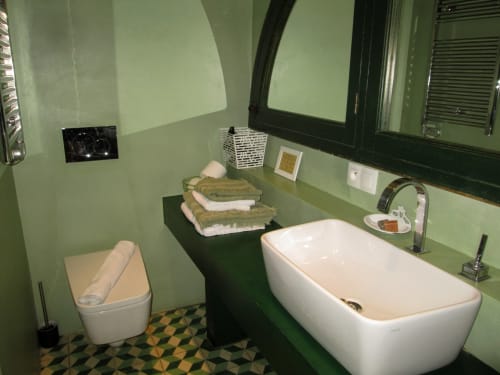 Bagno moderno presso Clos Bb con vasca bianca indipendente, pareti verdi, piastrelle geometriche e servizi a Saint-Cyr sur