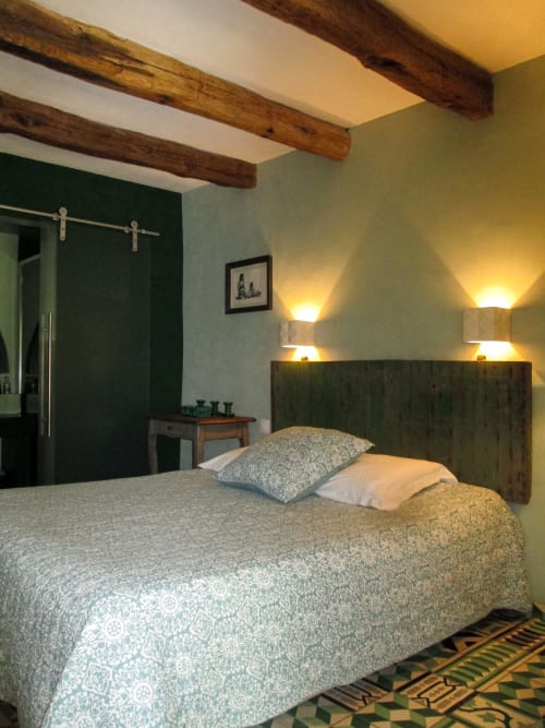 Chambre rustique à Clos BB à Saint-Cyr sur Mer avec poutres apparentes, tête de lit foncée et éclairage tamisé