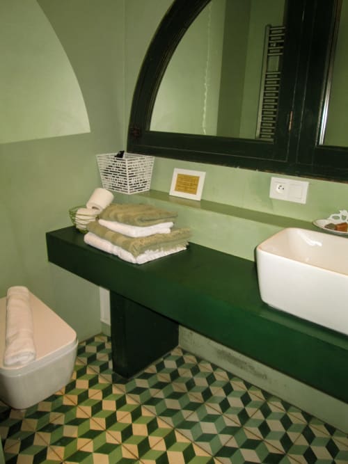 Bagno moderno presso Clos Bb con vanity verde, lavabo bianco, pavimento in piastrelle decorate e asciugamani color oliva a Saint-Cyr sur Mer