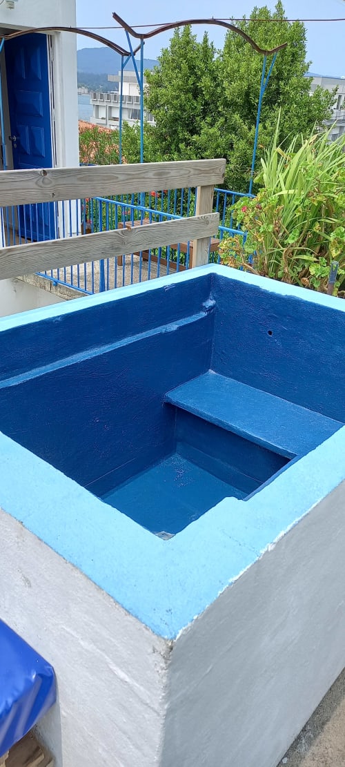 Empty blue swimming pool at Bom Caminha hostel in Caminha, Portugal with wooden deck and mountain views