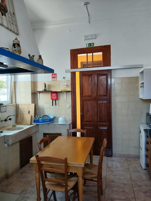 Bom Caminha hostel kitchen and dining area with wooden table, chairs, and cooking facilities in Caminha