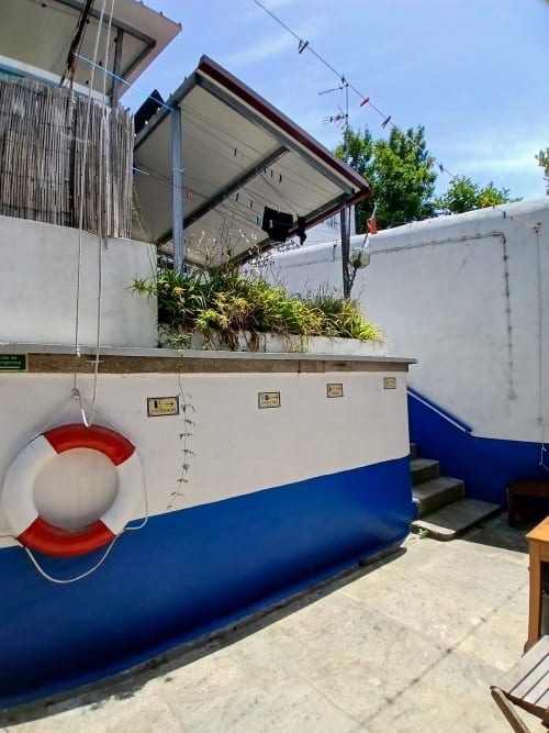 Bom Caminha hostel patio with blue boat-styled structure, life preserver, and potted plants in Caminha, Portugal
