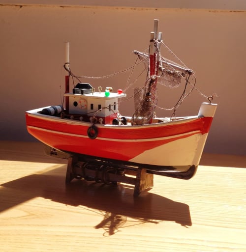 Wooden fishing boat model with red and cream hull displayed at Bom Caminha hostel in Caminha, Portugal