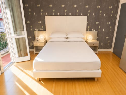 Camera moderna della B&B Pellicano Guest House a Reggio Calabria con letto bianco, comodini e carta da parati decorativa