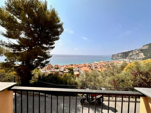 Vista dal balcone della costa di Finale Ligure con mare, tetti in terracotta, pineta e scogliere a Welcome Holiday