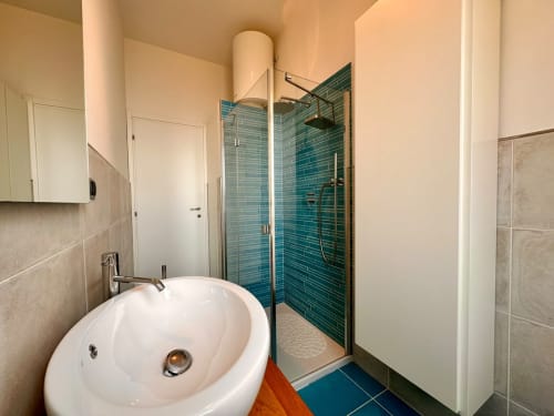 Bagno moderno nell'appartamento Welcome Holiday con lavabo rotondo bianco, box doccia in piastrelle turchesi e pavimento blu a Finale