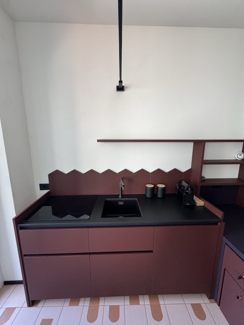 Cucina moderna con mobili bordeaux e piano di lavoro nero presso l'appartamento Porta Romana Suite Milano