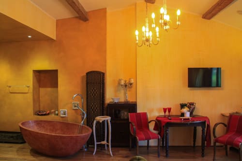 Lussuoso bagno spa giallo al Clos Bb con vasca in terracotta, sedie rosse e lampadario a Saint-Cyr sur Mer