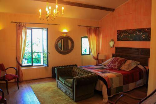 Camera accogliente con tonalità arancio presso la guest house Clos Bb a Saint-Cyr sur Mer, con lampadario, letto in legno scuro e vista sul giardino