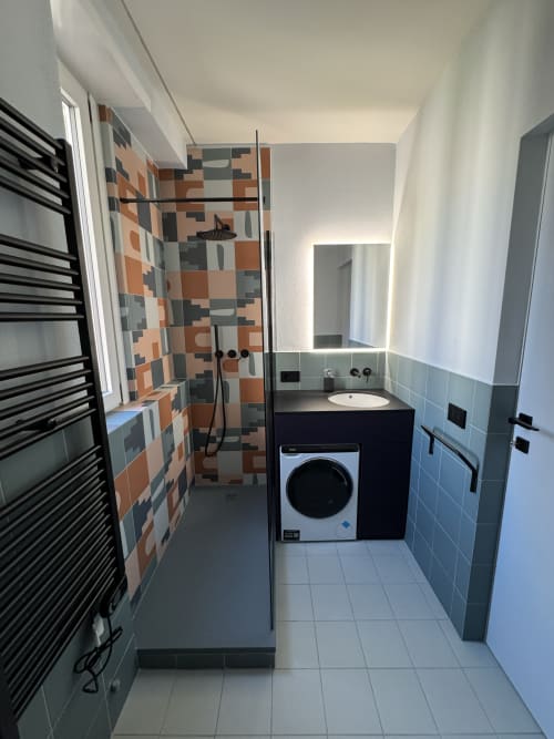 Bagno moderno della Porta Romana Suite Milano con doccia a piastrelle geometriche, vanità nera, lavatrice e scaldasalviette