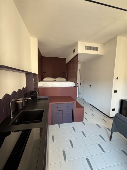 Monolocale moderno a Porta Romana Suite Milano con letto rialzato, angolo cottura e pavimento in piastrelle geometriche