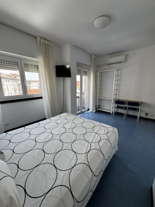 Luminoso monolocale a Porta Romana Suite Milano con letto, TV, balcone e pavimento in piastrelle blu