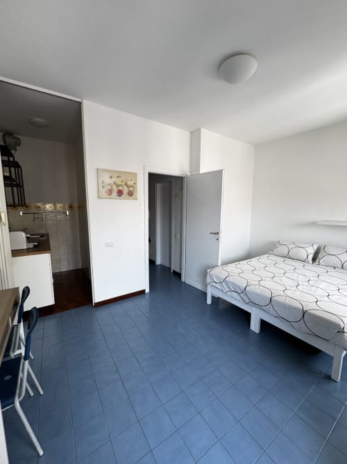 Luminoso monolocale a Porta Romana Suite Milano con letto, angolo cottura e pavimento in piastrelle blu