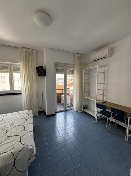 Luminoso monolocale a Porta Romana Suite Milano con letto, scrivania, ripiani, vista terrazza e comfort moderni