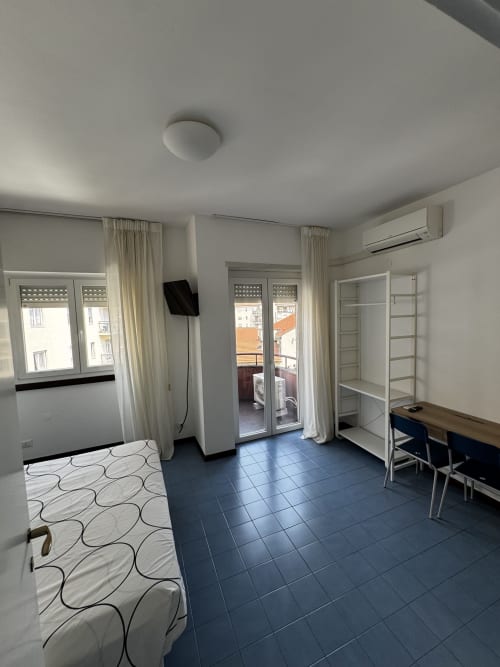 Luminoso monolocale a Porta Romana Suite Milano con letto, scrivania, accesso al balcone e pavimentazione in scuro