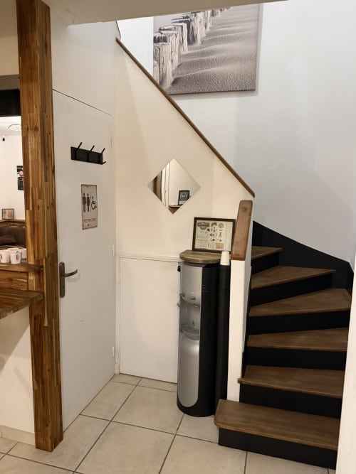 Escalier d'entrée à la Villa des Palmiers B&B à Villeneuve-sur-Lot, marches en bois, murs blancs et miroir décoratif
