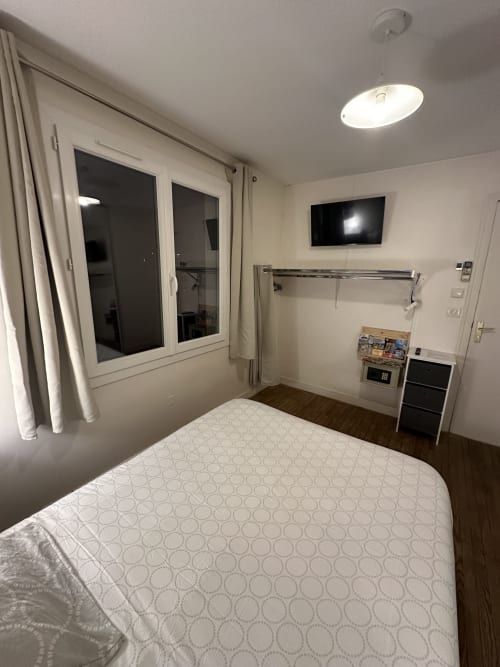 Chambre moderne à la Villa des Palmiers avec lit queen-size, TV murale et grande fenêtre, dans ce B&B de Villeneuve-sur-Lot
