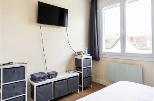 Chambre moderne à la Villa des Palmiers avec TV murale, rangements et vue sur le jardin par grandes fenêtres