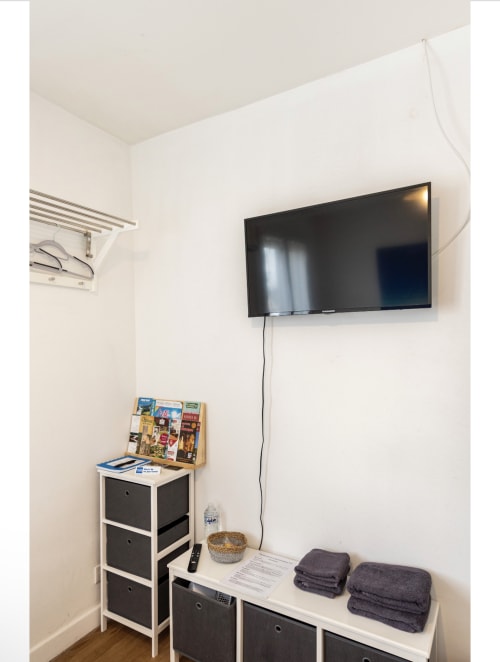 Téléviseur mural avec meuble de rangement, serviettes et magazines dans la chambre d'hôtes de Villa des Palmiers